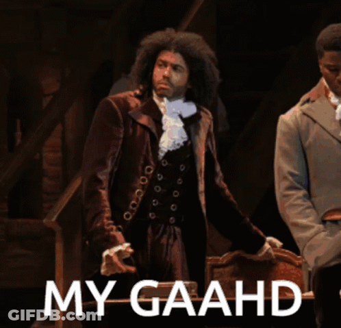 Man In Suit Standing Next To Chair Saying My Gaahd GIF