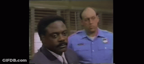 Man In Suit Standing Next To Police Officer In Blue Uniform GIF
