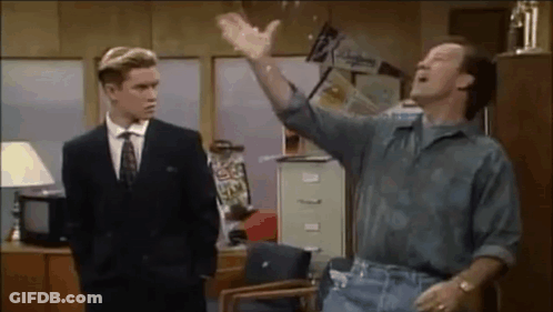 Man In Suit Standing Next To Seated Man In Office GIF