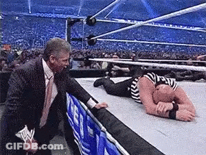 Man In Suit Standing Next To Wrestler On Floor GIF