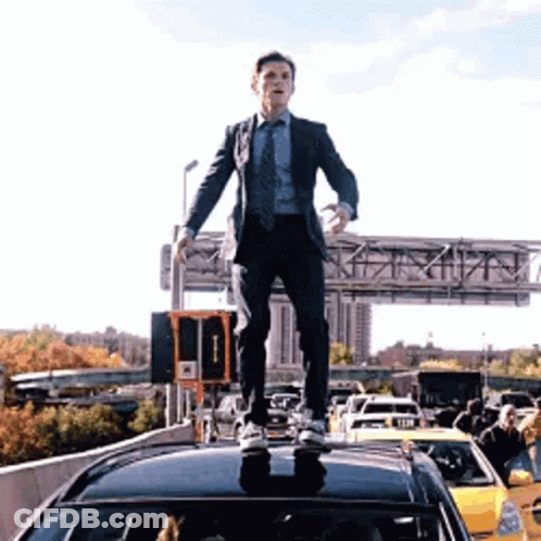Man In Suit Standing On Car On Highway GIF