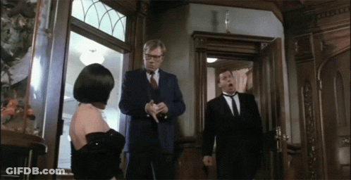Man In Suit Stands In Front Of Woman In Black Dress GIF