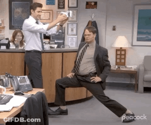 Man In Suit Stretching In Office While Another Takes Picture GIF