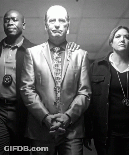 Man In Suit Surrounded By Police And Woman With Star Necklace GIF