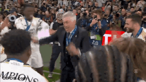 Man In Suit Surrounded By Soccer Champions GIF