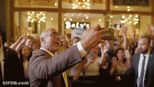 Man In Suit Taking Selfie In Front Of Bels Store GIF