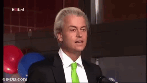 Man In Suit Talking Into Microphone With Green Tie GIF