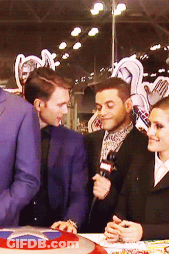 Man In Suit Talking Into Microphone Woman Looking On GIF