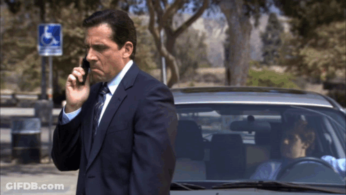 Man In Suit Talking On Cell Phone Near Handicapped Sign GIF