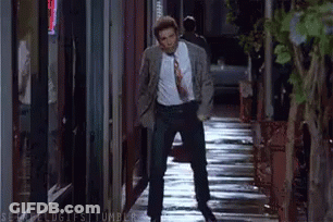 Man In Suit Talking On Cell Phone Walking Wet Sidewalk GIF