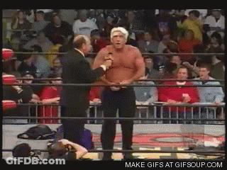 Man In Suit Talking To Another In Wrestling Ring With Crowd GIF