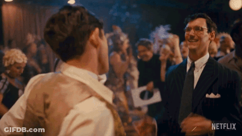 Man In Suit Talking To Another Man In Crowded Room GIF