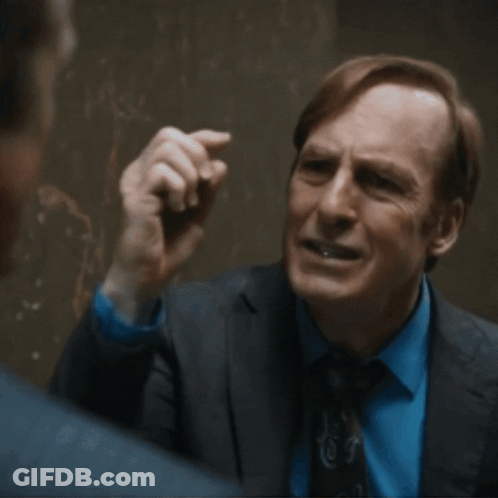 Man In Suit Talking To Another Man In Dark Room GIF
