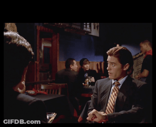 Man In Suit Talking To Another Man With Gotten Us In Behind Him GIF