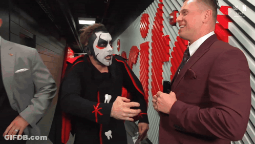 Man In Suit Talking To Costumed Man GIF