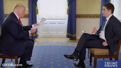 Man In Suit Talking To Man In Chair Trump Draws Sign GIF