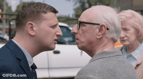 Man In Suit Talking To Older Man In Glasses GIF