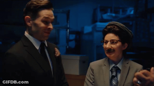 Man In Suit Talking To Woman In Glasses GIF