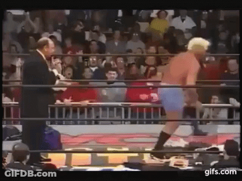 Man In Suit Talking To Wrestler In Blue Shorts GIF