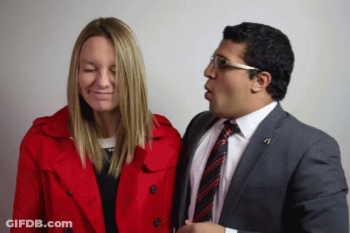 Man In Suit Talks To Woman In Red Trench Coat GIF
