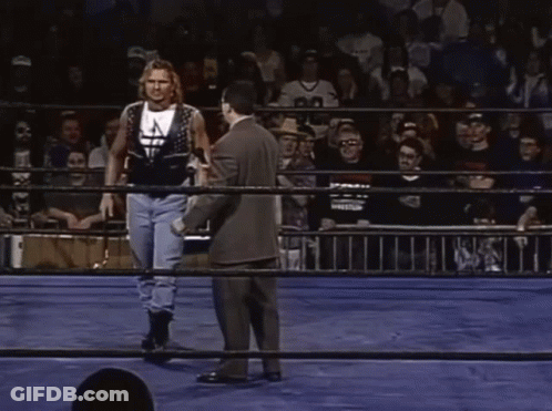 Man In Suit Talks To Wrestler In Ring With Crowd GIF