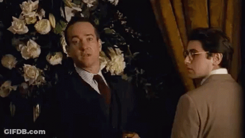 Man In Suit Thumbs Up Beside Man In Brown Sweater GIF