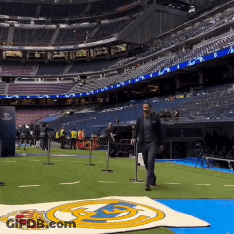 Man In Suit Walking Across Soccer Field GIF