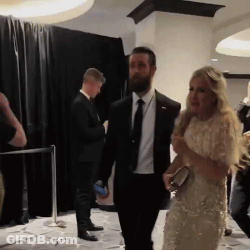 Man In Suit Walking Beside Woman In White Dress GIF