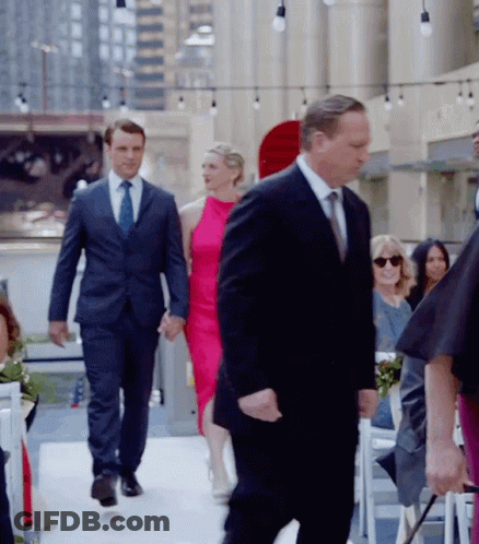 Man In Suit Walking Down Aisle Holding Hands With Woman In Pink Dress GIF