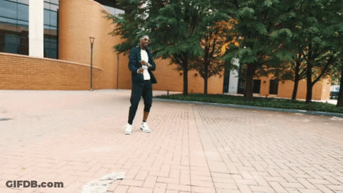 Man In Suit Walking Down Brick Street GIF