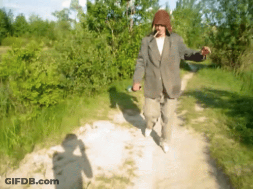 Man In Suit Walking Down Dirt Path Smoking Cigarette GIF