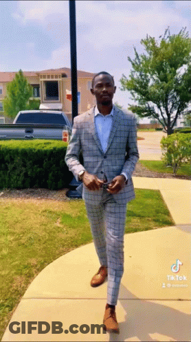 Man In Suit Walking Down Sidewalk With TikTok Watermark GIF
