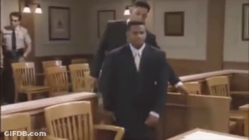 Man In Suit Walking In Courtroom With Man Behind GIF