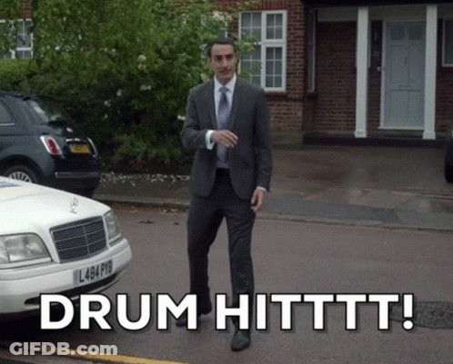 Man In Suit Walking Next To White Car Saying Drum Hitttt GIF