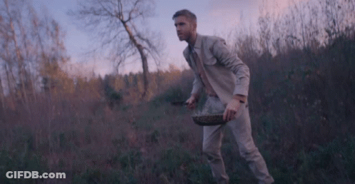 Man In Suit Walking Through Field With Basket GIF