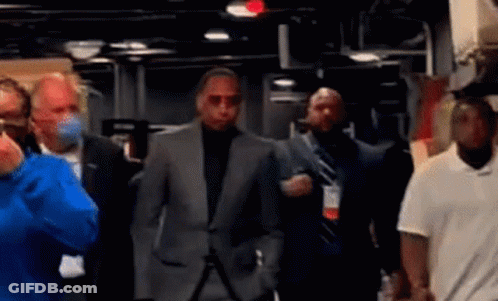 Man In Suit Walking Through Masked Crowd GIF