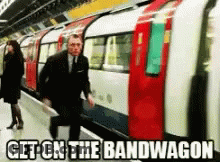 Man In Suit Walking To Train Saying Get On The Bandwagon GIF