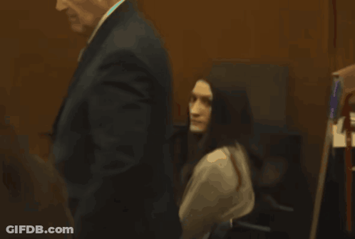Man In Suit Walks Past Woman In Chair GIF