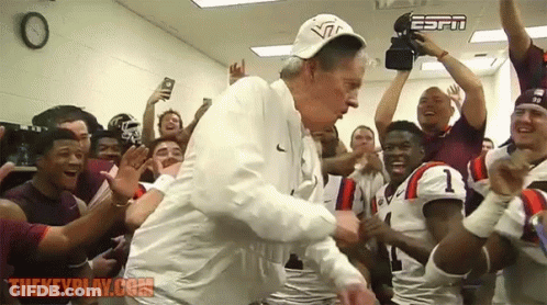 Man In Suit Watching Football With Frank Beamer Above GIF