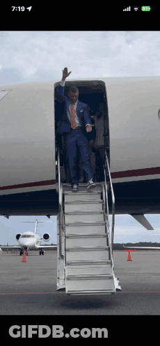 Man In Suit Waving From Plane Stairs GIF