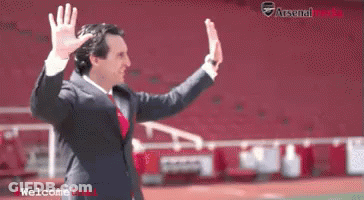 Man In Suit Waving In Front Of Arsenal Stadium GIF