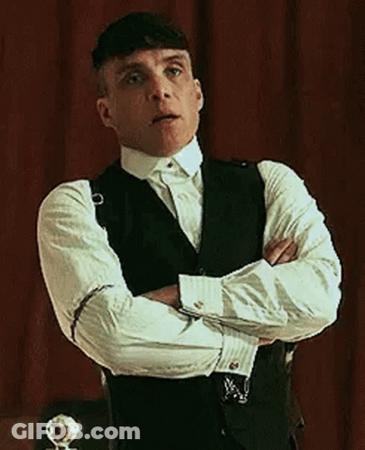 Man In Suit With Arms Crossed In Front Of Red Curtain GIF