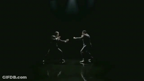Man In Suit With Arms Outstretched In Dark Room GIF