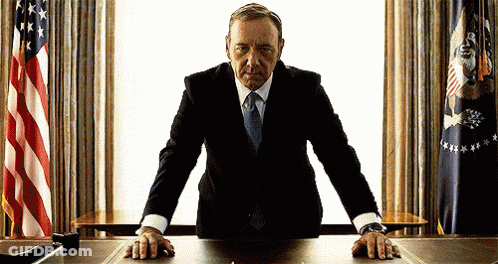 Man In Suit With Hands On Desk GIF