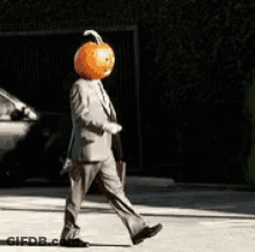 Man In Suit With Pumpkin Head Walking Down Street GIF