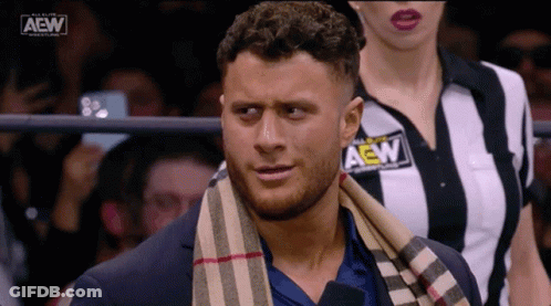 Man In Suit With Scarf And Woman In Striped AEW Shirt GIF