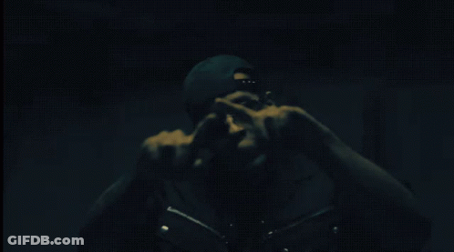Man In Sunglasses And Beanie Pointing In Dark GIF