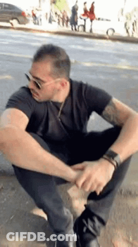 Man In Sunglasses And Black Shirt Squatting GIF
