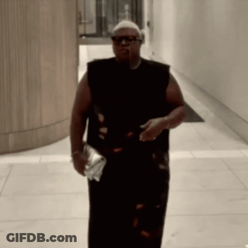 Man In Sunglasses And Black Tank Top Walking Down Hallway GIF