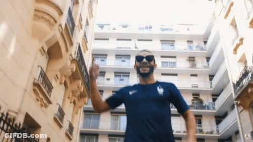 Man In Sunglasses And Blue Shirt In Front Of Building GIF